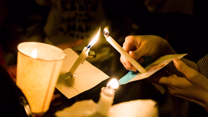 Primo piano di candele accese durante una veglia in occasione del Transgender Day of Remembrance, in memoria delle vittime della transfobia.