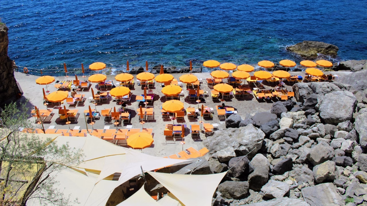 Stabilimento balneare One Fire Beach a Praiano nella Costiera Amalfitana, noto come spiaggia gay friendly della Campania con lettini arancioni a ridosso del mare cristallino e ambiente accogliente LGBTQ+.