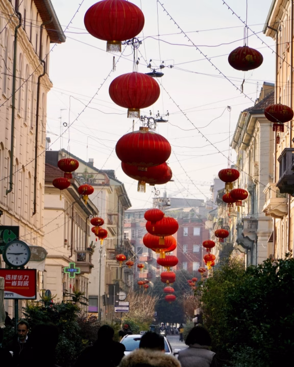 Lanterne rosse sospese lungo via Paolo Sarpi, il cuore di Chinatown a Milano. La strada &egrave; addobbata per le celebrazioni del Capodanno cinese, creando un&rsquo;atmosfera suggestiva tra edifici storici, negozi e ristoranti dove gustare autentica cucina cinese.