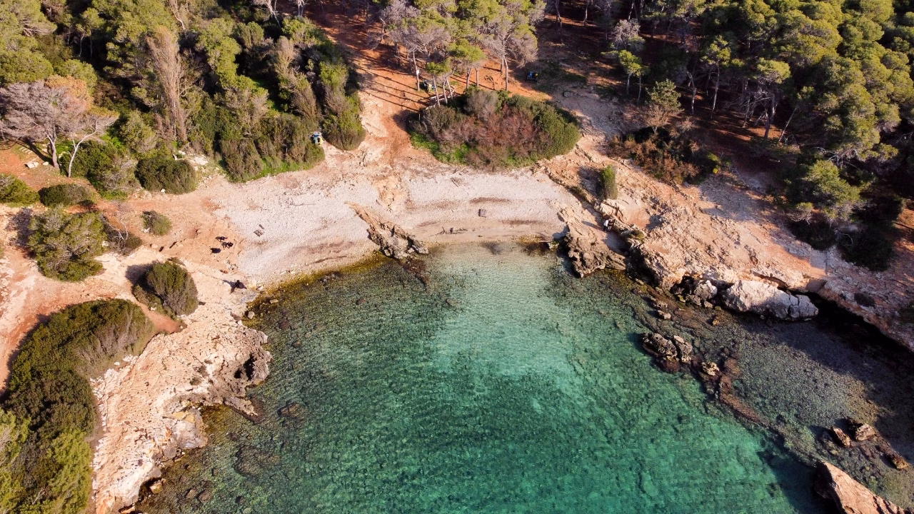 Veduta aerea della caletta di Porto Selvaggio vicino a Torre Uluzzo, nel Salento, con acque cristalline e scogliere rocciose circondate dalla pineta. Una delle spiagge gay e naturiste pi&ugrave; amate nei dintorni di Gallipoli.