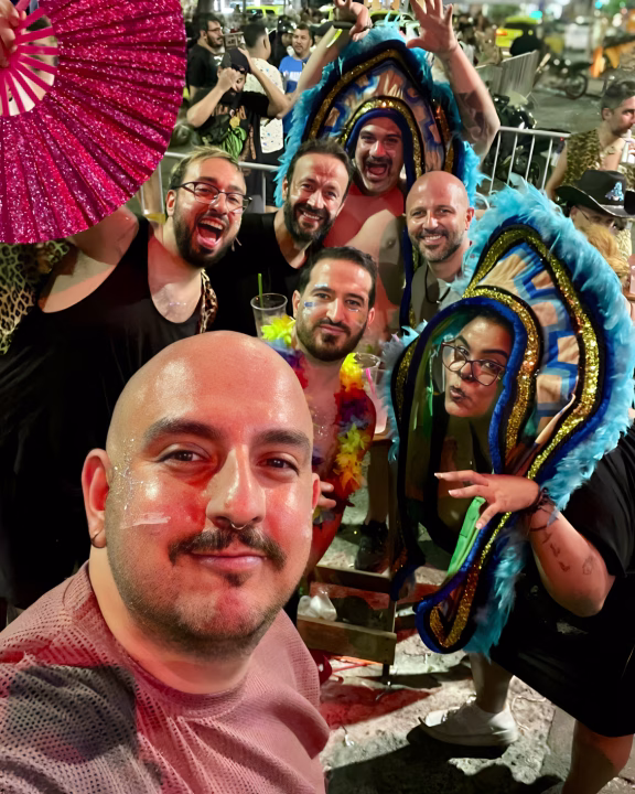 Un gruppo di amici in festa posa con sorrisi, glitter e costumi carnevaleschi tra piume colorate e drink alla mano durante il Carnevale LGBTQ+ di Rio de Janeiro. L&rsquo;atmosfera &egrave; vibrante e gioiosa, perfetta per celebrare l&rsquo;orgoglio queer nella capitale del divertimento brasiliano.