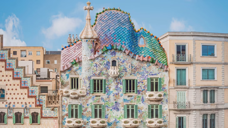Facciata coloratissima di Casa Batll&oacute; a Barcellona, capolavoro architettonico firmato Antoni Gaud&iacute;, decorata con mosaici iridescenti, forme organiche e balconi ondulati. Il tetto ricorda le squame di un drago, simbolo distintivo dello stile modernista catalano.