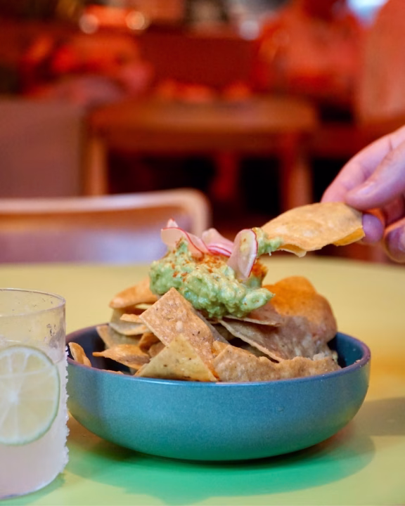 Ciotola di nachos con guacamole, cipolla e paprika servita con margarita al lime al ristorante Madre di Manchester, locale inclusivo consigliato nella guida LGBTQ+.