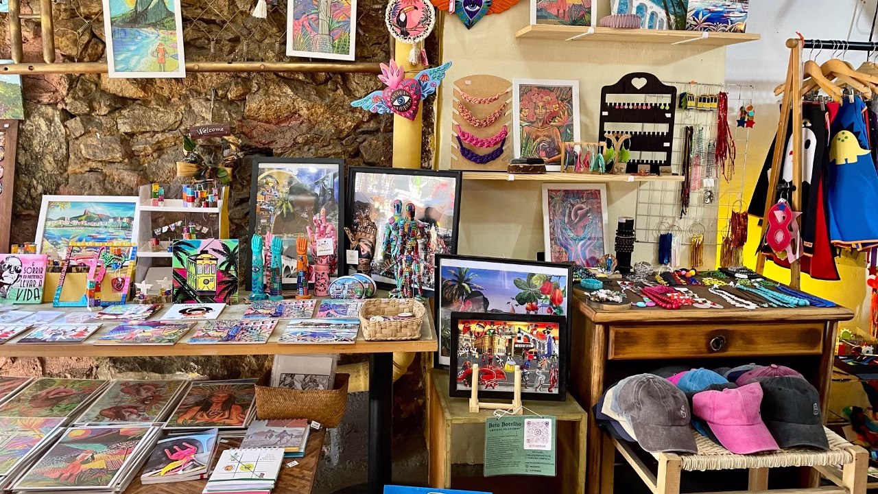 Un vivace negozio creativo a Rio de Janeiro espone stampe artistiche, oggetti decorativi, bigiotteria colorata, cartoline, cappellini e abiti originali. L&rsquo;ambiente trasmette un&rsquo;estetica queer e artigianale, con riferimenti pop e tropicali che celebrano la cultura locale e l&rsquo;inclusivit&agrave;.