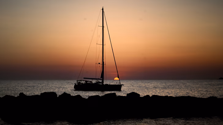 Una barca a largo mentre il sole tramonta di fronte a Gallipoli in Salento, Puglia