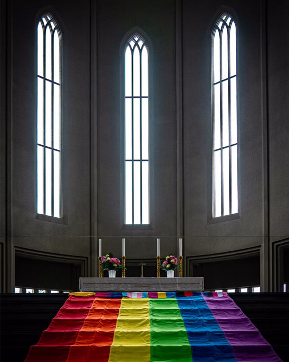 Interno della Hallgr&iacute;mskirkja di Reykjavik con bandiera arcobaleno sull&rsquo;altare durante il Pride, simbolo dell&rsquo;inclusivit&agrave; LGBTQ+ in Islanda.