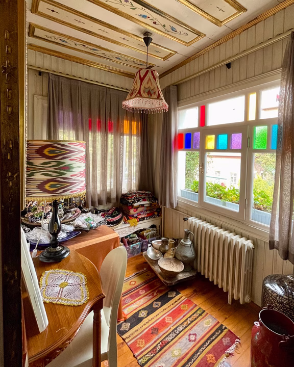 Negozio di artigianato tradizionale a Istanbul con tappeti colorati, lampade dipinte a mano, oggetti in metallo e tessuti tipici esposti in un&rsquo;accogliente stanza decorata con vetri colorati e dettagli in stile ottomano.