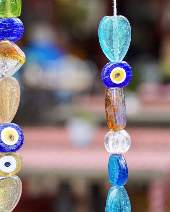 Dettaglio di una collana artigianale realizzata con perle di vetro colorate e amuleti Nazar, simboli tradizionali turchi contro il malocchio, esposti in un mercato di Istanbul.