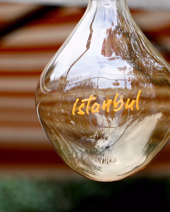 Primo piano di una lampada di vetro con la scritta &ldquo;Istanbul&rdquo; riflettente l&rsquo;ambiente circostante, simbolo di accoglienza nei vivaci quartieri LGBTQ+ della citt&agrave; come Beyoğlu, Cihangir e Kadık&ouml;y.