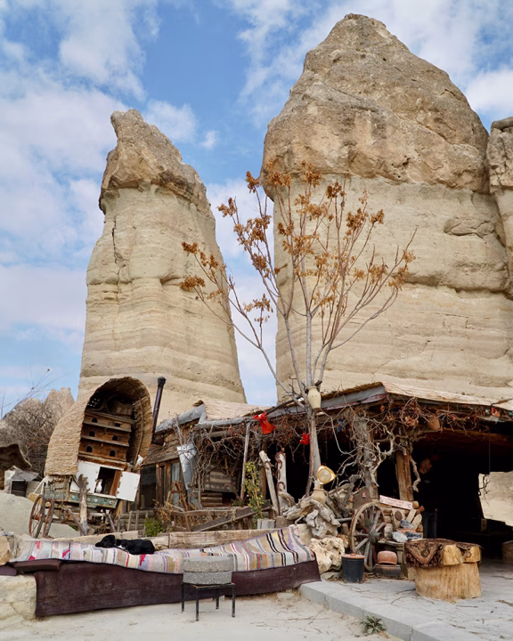 Caffetteria rustica scavata nella roccia tra le formazioni rocciose iconiche della Cappadocia, con arredi in legno, tappeti tradizionali e atmosfera suggestiva