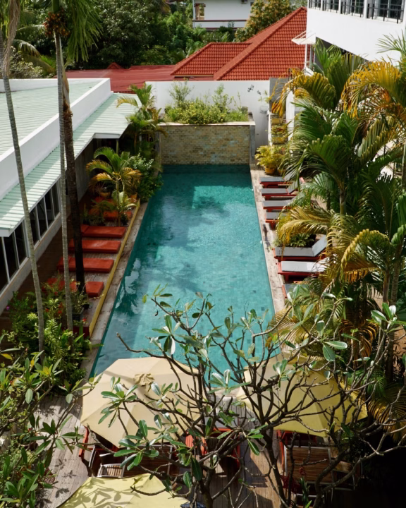 Vista dall&rsquo;alto della piscina tropicale del Men&rsquo;s Resort & Spa di Siem Reap, circondata da palme e lettini, cuore dell&rsquo;hotel gay-only della Cambogia.