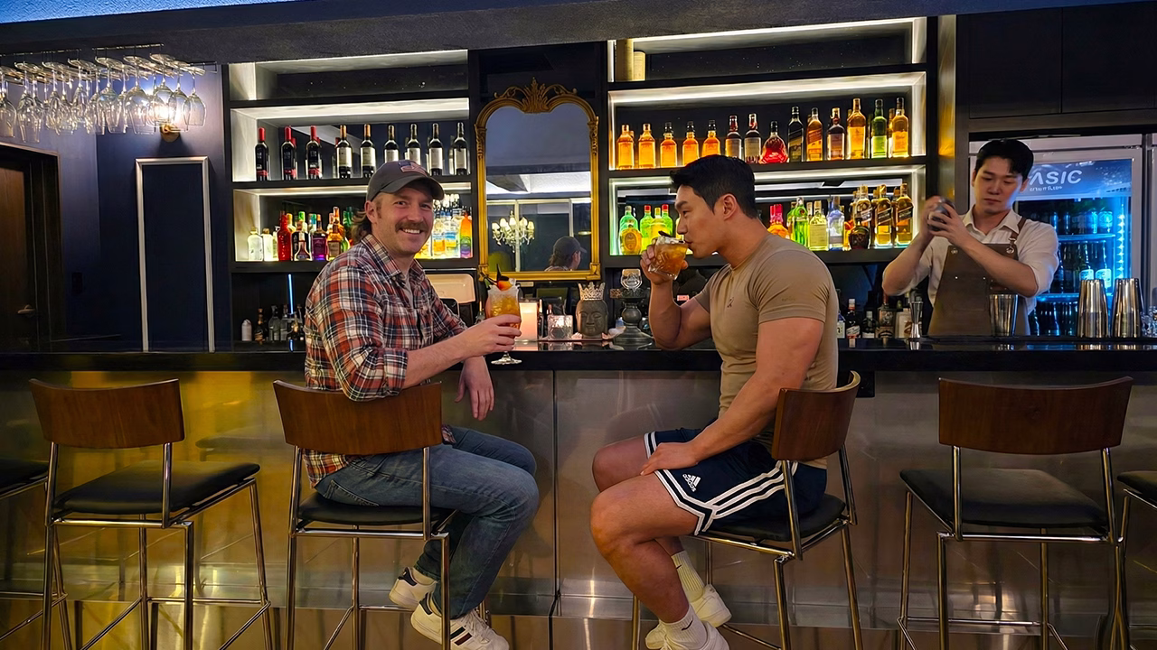 Una coppa di ragazzi gay in un bar gay a Busan, tra cocktail e atmosfera conviviale, esplorando la vita notturna gay di Beomil-dong