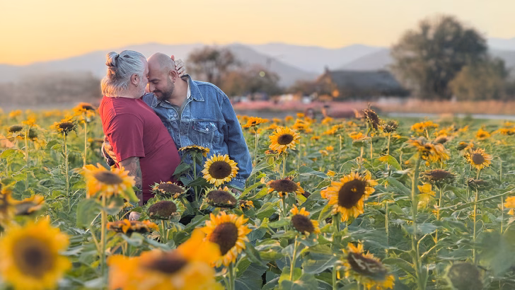 Daniele e Luigi di Gayly Planet che si abbracciano in un campo di girasoli in Corea del Sud al tramonto, viaggio LGBTQ+ in un contesto naturale e sicuro