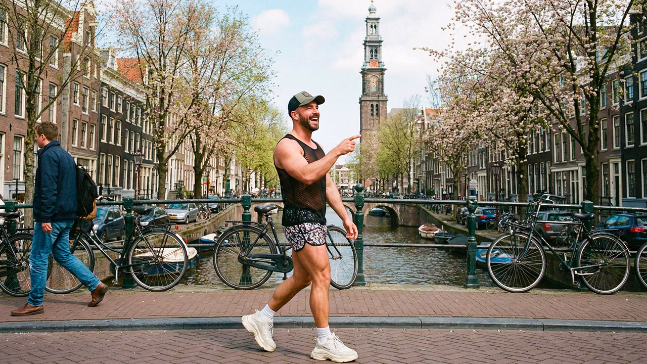Viaggiatore gay passeggia lungo i canali di Amsterdam in primavera, tra alberi in fiore e atmosfera LGBTQ+ friendly