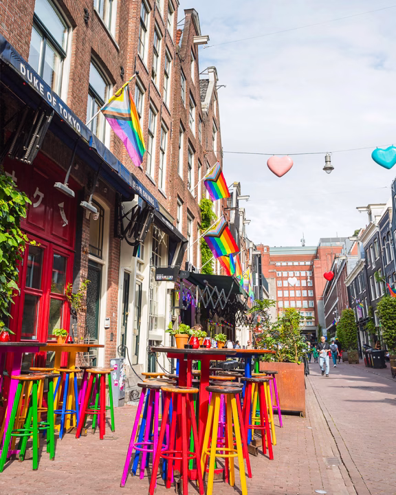 Reguliersdwarsstraat Amsterdam con bandiere arcobaleno e bar colorati, cuore della nightlife gay e quartiere LGBTQ+