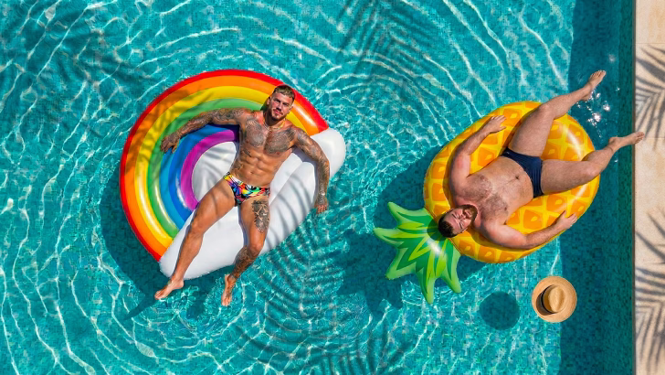 due uomini rilassati su gonfiabili colorati in piscina in un hotel gay friendly a Ibiza, atmosfera estiva e LGBTQ+ inclusiva