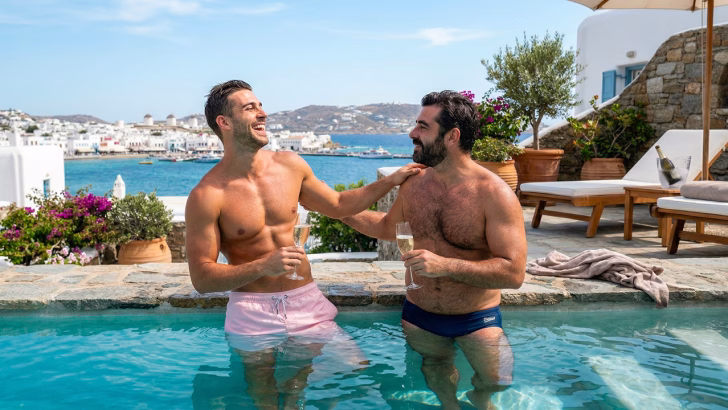 coppia gay in piscina con vista su Mykonos Town, esperienza hotel gay friendly Mykonos tra relax e lifestyle LGBTQ+