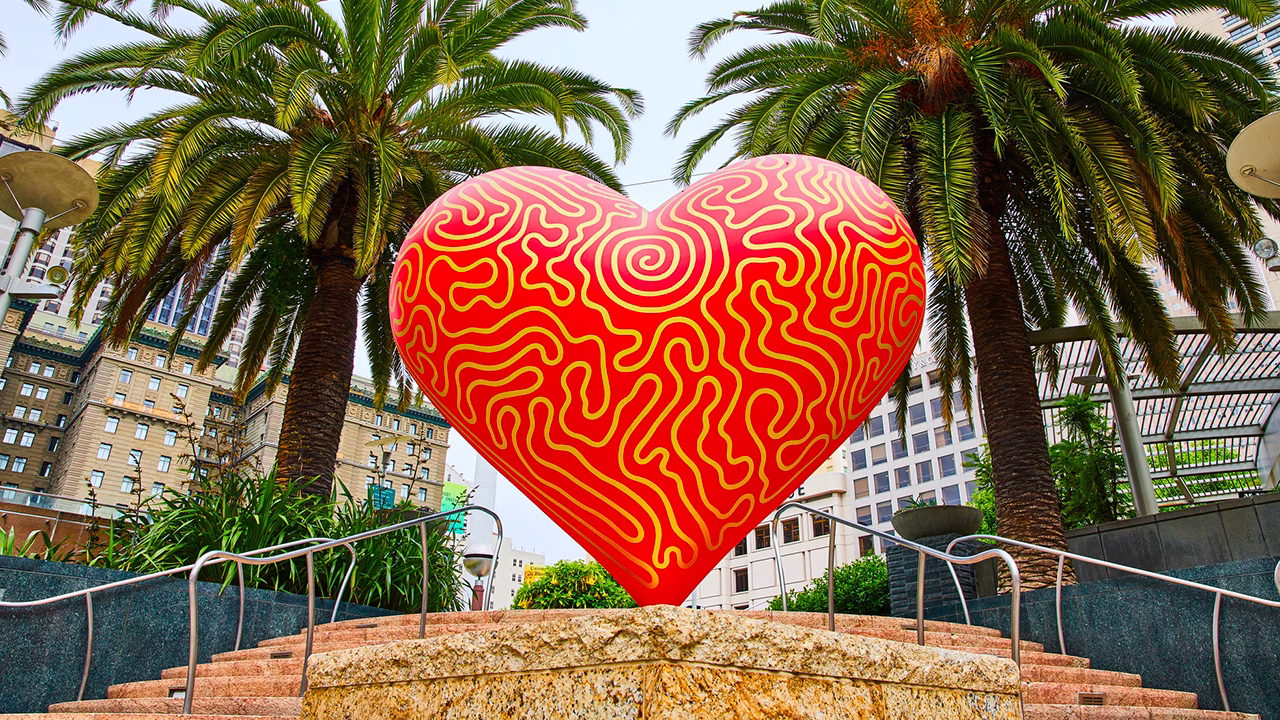 Cuore rosso iconico a Union Square tra palme e grattacieli, simbolo di San Francisco gay friendly