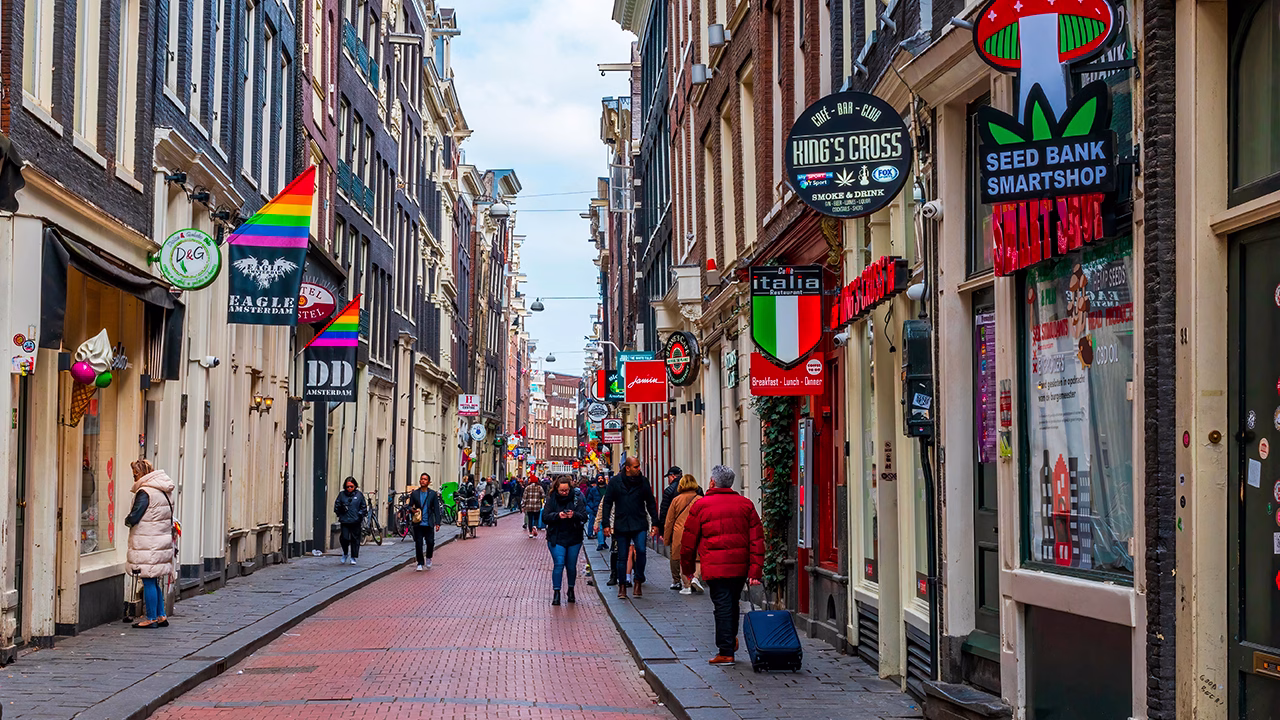 Warmoesstraat Amsterdam con bandiere arcobaleno e locali storici come Eagle e Dirty Dicks, zona centrale della nightlife gay